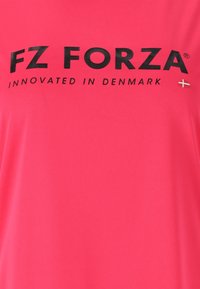 Kirjavan vaaleanpunaisen kankaan päällä on suurilla mustilla kirjaimilla teksti "FZ FORZA" ja pienemmällä tekstillä "INNOVATED IN DENMARK", jossa on pieni Tanskan lippu -ikoni.