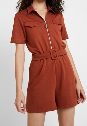Kortærmet, rustfarvet jumpsuit lavet af blødt materiale. Har lynlås foran, to brystlommer og talje med bælte.