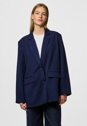 Marineblå oversized blazer med klapkrave, to forlommer og en enkelt knaplukning. Blød stof med en glat tekstur.