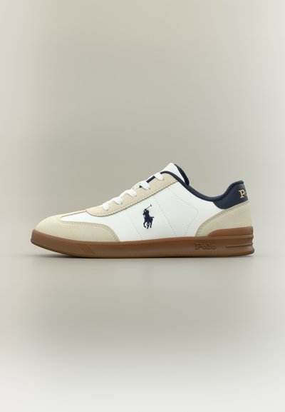 Λευκό και μπεζ sneaker χαμηλού προφίλ με καφέ σόλα, ναυτικό μπλε λεπτομέρειες, λευκά κορδόνια και σκούρο μπλε λογότυπο Polo Ralph Lauren στο πλάι και στη φτέρνα.