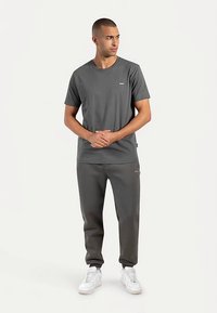 Gray T-shirt and gray sweatpants, both made of soft cotton. T-shirt features a small logo; sneakers are white with a sleek design.
