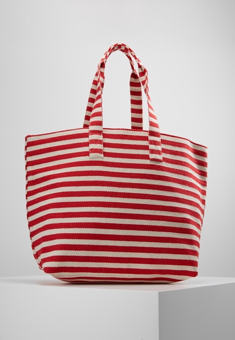 Sac fourre-tout rayé avec des rayures horizontales rouges et crème, fabriqué en tissu durable, doté de deux poignées robustes et d'un design spacieux.
