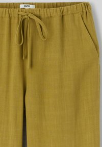Pantalons khaki à coupe décontractée, en tissu texturé. Comprend une taille élastique avec cordon de serrage et des poches latérales.