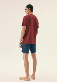 Czerwona bawełniana koszulka z krótkim rękawem, w połączeniu z granatowymi szortami. Prosty wzór, bez widocznych motywów czy ozdób.