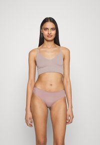 Bralette côtelée marron clair avec bretelles ajustables et décolleté en V, assortie à un bas de bikini seamless marron clair. Tissu doux et extensible.