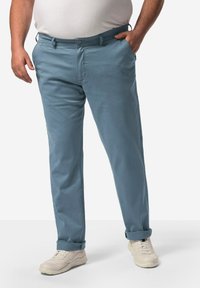 Ljusblå chinos i bomull med rak bendesign, sidofickor och uppvikt fåll. Bärs med ljusa sneakers.