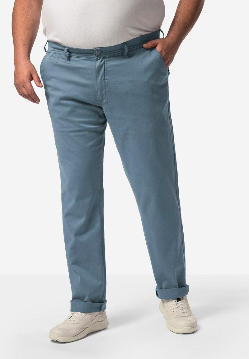 Ljusblå chinos i bomull med rak bendesign, sidofickor och uppvikt fåll. Bärs med ljusa sneakers.