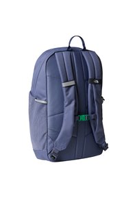 Marineblå ryggsekk med polstret stoff, nettinglommer på sidene og justerbare stropper. Har en grønn spenne og reflekterende detaljer for synlighet.