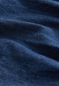 Donkerblauwe denimstof met een licht gestructureerd oppervlak, subtiele kleurvariaties en een zachte, geweven uitstraling.