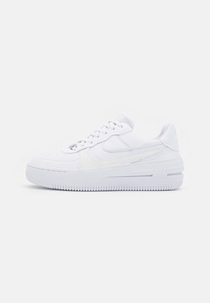 White athletic sneakers with a smooth leather upper, textured sole, padded collar, and perforations on the toe. Features minimal branding.