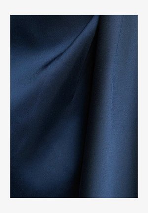 Primo piano di tessuto blu scuro liscio con pieghe morbide e cuciture sottili lungo un bordo.