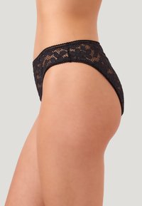 Svart spetsunderkläder med blomsterdesign, mjukt material och en slät midjeband, designade i låg midja.