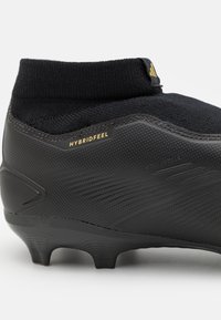 Scarpino da calcio nero con upper sintetico testurizzato, colletto a calza in maglia e tacchetti per la trazione, con la scritta "HYBRIDFEEL" in lettere dorate.