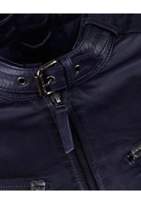 Marineblaue Lederjacke mit Reißverschluss vorne, metallischen Hardware-Akzenten und dekorativer Naht an Kragen und Schultern.