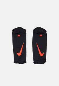 Mustmust võrkkatsega spordivarrukad, millel on kontrastne punane Nike suts ja venivad avad, pakkudes tihedat istuvust.