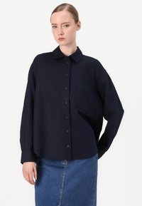 Navyblauw overhemd met knopen, met een kraag, lange mouwen, een enkele borstzak en een relaxte pasvorm, gemaakt van lichtgewicht stof.