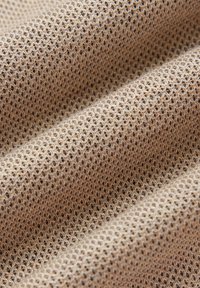 Beżowy materiał o delikatnej, plasterkowej strukturze, ukazany w miękkich fałdach i z bliska.