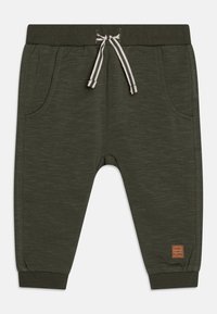 Ciemnozielone dresy z teksturowanej tkaniny, elastycznym paskiem w talii, sznurkiem ściągającym i bocznymi kieszeniami. Posiadają małą naszywkę marki na nogawce.