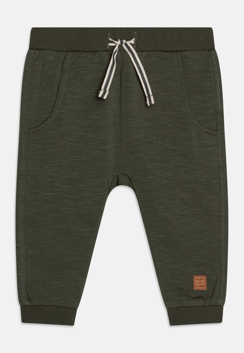 Ciemnozielone dresy z teksturowanej tkaniny, elastycznym paskiem w talii, sznurkiem ściągającym i bocznymi kieszeniami. Posiadają małą naszywkę marki na nogawce.