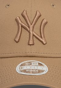 Μπεζ καπέλο μπέιζμπολ με έντονο κεντημένο λογότυπο NY σε αντίστοιχη απόχρωση. Διαθέτει καμπυλωτό γείσο και ρυθμιζόμενο λουράκι στο πίσω μέρος.