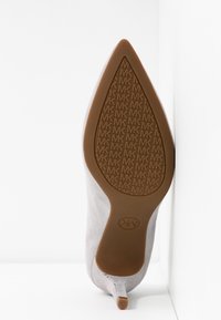 Talons en daim gris avec un bout pointu et une semelle en caoutchouc arborant un motif MK embossé. La semelle est de couleur brune et a un design effilé.