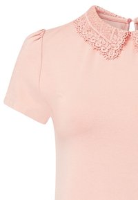 Ljust rosa kortärmad t-shirt med en virkadelacekrage och en knappstängning på baksidan, tillverkad av mjukt bomullstyg.