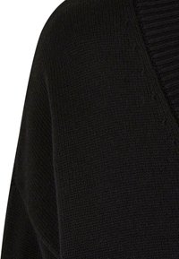 Close-up of black knitted fabric with ribbed detailing along a seam, showing texture and stitch patterns.