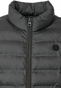 Schwarze gepolsterte Jacke mit hohem Kragen, Frontreißverschluss und einem runden Logodetail. Glatte Textur und durchgehendes Steppmuster.