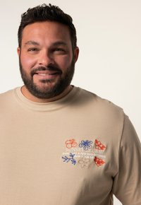 Béžové bavlněné tričko s vyšívanými květinovými vzory v oranžové, modré a červené barvě, s textem "SUNSET CLUB 07" a sloganem.