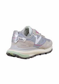 Zapatilla gris y rosa claro con parte superior de ante y malla. Presenta una suela intermedia blanca gruesa y una suela exterior negra texturizada. Acento metálico en el talón.