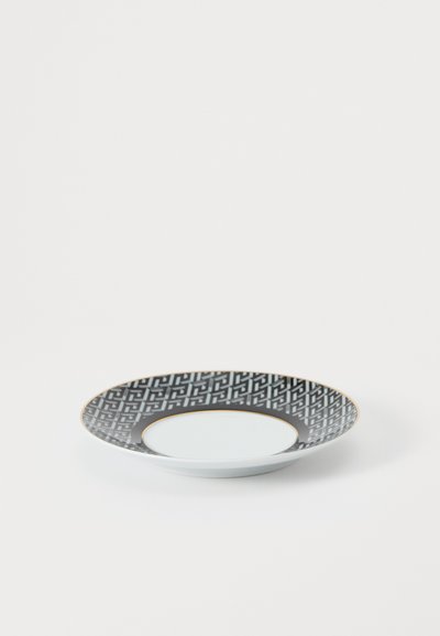 Okrągły talerz z porcelany. Posiada czarny geometryczny wzór z złotą obręczą i gładkim białym środkiem. Gładka, błyszcząca tekstura.