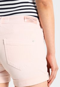 Světle růžové denim šortky s ohrnutým lemem, se zadní kapsou a štítkem se nápisem "Freeman T. Porter."