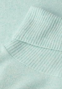 Tissu tricoté bleu clair avec un détail de bord-côte, montrant la texture et des couches pliées.