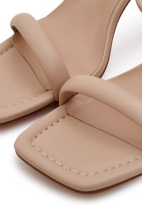 Nude nahka sandaalit neliön muotoisella kärjellä, joissa on kaksi ohutta hihnaa ja tikattu pohja. Pintakuvio on sileä ja mattapintainen.