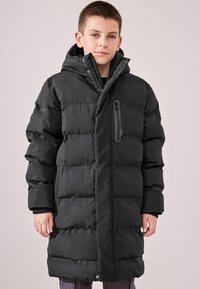 Manteau long noir rembourré avec capuche, fermeture éclair à l'avant et poches latérales. Présente un tissu texturé et un design épuré.