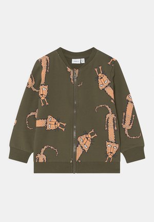 Veste à fermeture éclair pour enfant couleur vert olive avec des imprimés guépard orange de style cartoon dispersés sur le devant et les manches.