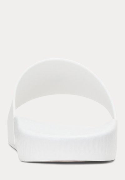 Hvit slip-on sandal med bredt enkelt stropp og teksturert såle, vist forfra på en ensfarget bakgrunn.