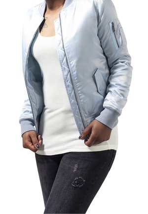 Light blue satin bomber jacket with ribbed cuffs, side pockets, and a zippered arm pocket, paired with a white t-shirt and dark jeans.