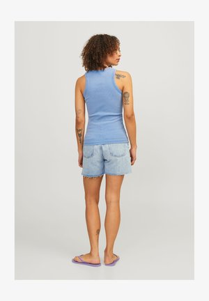 Blå ribbet tanktop med en tætsiddende pasform, parret med slidte lyse denimshorts; modellen står med ryggen til og har lilla flip-flops på.