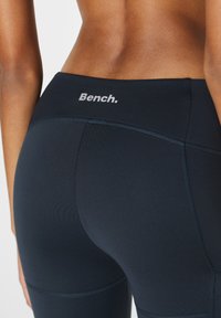 Dunkelblaue Leggings mit glatter Textur, enganliegendem Design und kontrastierendem, hellgrauem "Bench."-Logo am Bund.