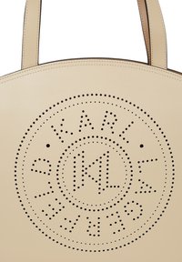 Bézs bőrtáska körkörösen perforált logómintával és varrott szélekkel, amelyen a "STELLA MCCARTNEY" felirat olvasható.