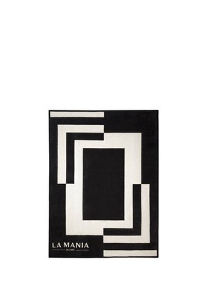 Czarnobiały dywan o geometrycznym wzorze z prostokątnymi kształtami i napisem „LA MANIA HOME” w lewym dolnym rogu.