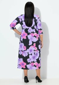 Maxi šaty s černým pozadím a velkými fialovými a růžovými květinovými vzory, tříčtvrtečními rukávy a zúženým pasem.