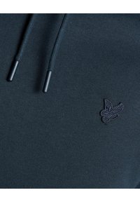 Felpa navy con cappuccio realizzata in un morbido tessuto testurizzato, dotata di coulisse e di un piccolo logo ricamato sul petto. Design semplice e minimale.