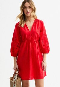Rode jurk met een V-hals, met pofmouwen en bloemmotieven borduursel. Gemaakt van lichtgewicht stof, met een losse, vloeiende ontwerpe.