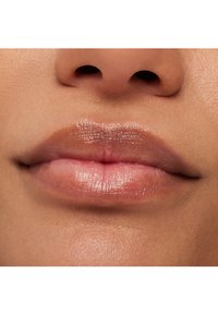 Glänzender Lippenstift mit einem natürlichen, rosa Farbton, glatter Textur und subtiler Ausstrahlung. Nahaufnahme des Mundbereichs, die die Lippen und Haut betont.