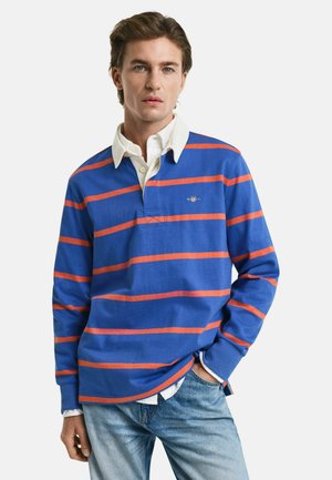 Blue long-sleeve polo shirt with orange horizontal stripes and white collared shirt underneath. The fabric appears soft with a relaxed fit.