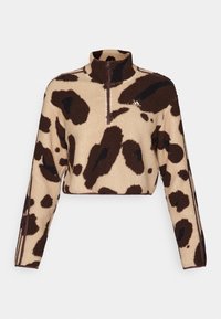 Kortad pullover i beige fleece med brunt djurmönster; har en hög krage och framficka med halvlång dragkedja. Subtilt varumärke på bröstet.