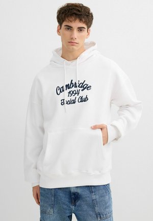 Sudadera con capucha blanca con texto bordado en color azul marino "Cambridge 1994 Social Club", bolsillo canguro, capucha con cordón y corte relajado. Textura de tela ligera.