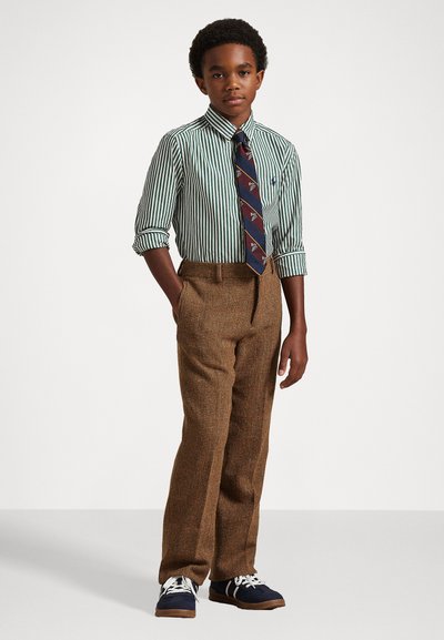 Črtasta zelena in bela srajca z dolgimi rokavi, rjave hrapave hlače in mornarsko modri čevlji. Ima vzorčasto kravato z različnimi oblikami.